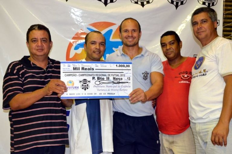 A foto destaca autoridades e o representante da equipe campeã de futsal