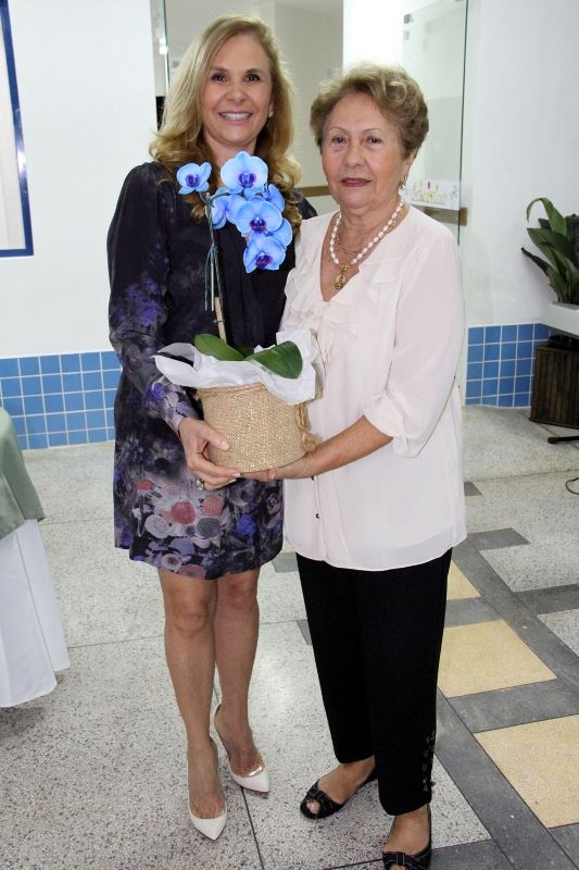 Foto: A Senhora Ana Lucia Camargo Farhat recebendo um vaso de flor  