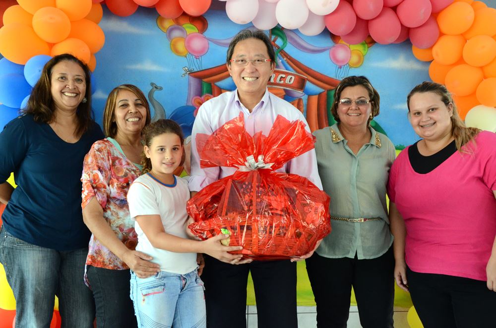 O Prefeito Arnaldo Enomoto entrega uma cesta para aluna Natália Gomes